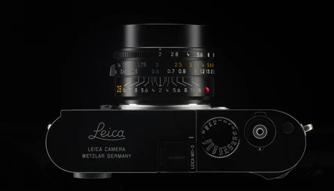 Top-down view of a Leica rangefinder camera with mounted lens against a black background.