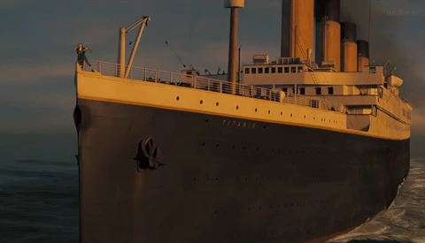Large ocean liner with yellow superstructure and dark hull positioned at a dock during golden hour.