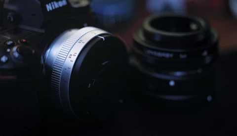 Nikon camera with silver lens in sharp focus, additional lens blurred in background.