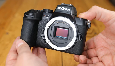 Nikon Z mirrorless camera held in hands, showing open sensor with white mirror box frame visible.