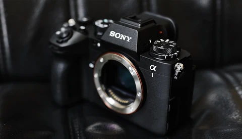 Sony α mirrorless camera body with exposed sensor and mount, displayed against dark fabric backdrop.