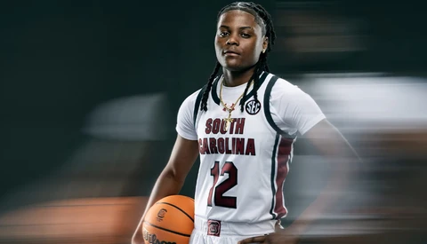 Basketball player wearing South Carolina white jersey number 12 holding a basketball.