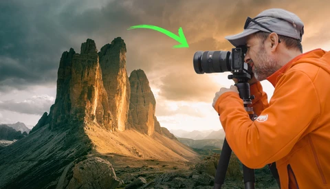Photographer in orange jacket photographing dramatic mountain peaks during golden hour.