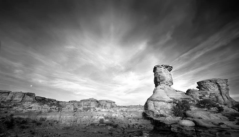 Weathered rock formations rising from an arid desert landscape beneath a dramatic cloudy sky.