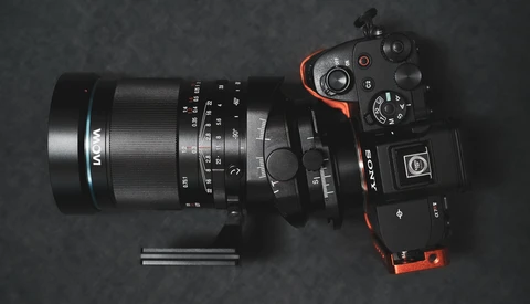 Mirrorless camera with macro lens and extension tubes arranged on dark surface.