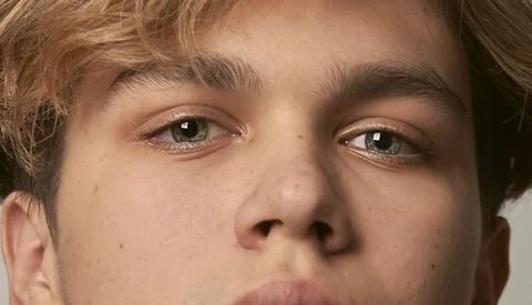Close-up portrait of a young man with direct eye contact and neutral expression.