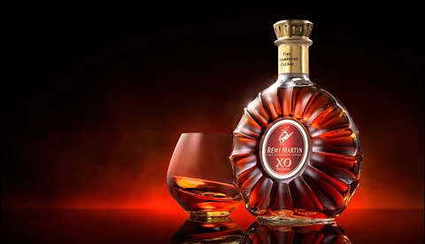 Cognac bottle and snifter glass against warm amber-lit background.