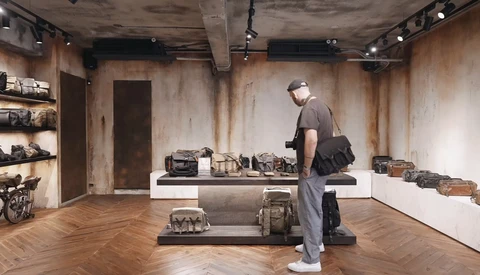 Visitor examines vintage cameras displayed on central platform in minimalist gallery space.