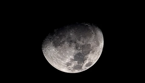 Waxing gibbous moon showing detailed surface features against black sky.