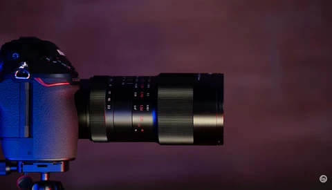 Telephoto lens mounted on blue camera body against purple background.