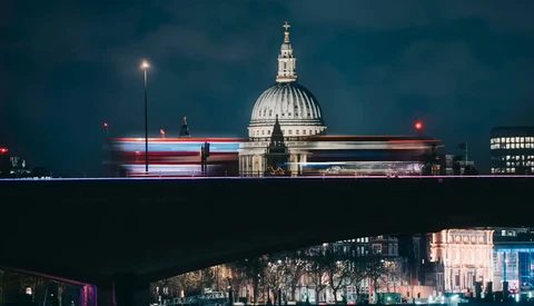 St. Paul's Cathedral at night with a light-trail from a passing bus creating red and blue streaks across the illuminated dome.