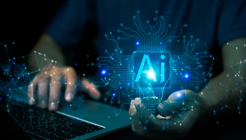 Hands holding a laptop and smartphone with glowing AI hologram and circuit board network visualization.