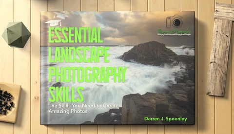 Book cover for 'Essential Landscape Photography Skills' by Darren J. Spoonley featuring a dramatic coastal landscape.