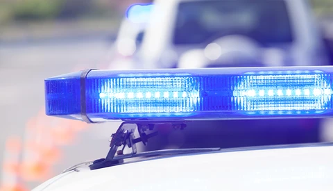 Blue LED emergency light bar on a police vehicle with bokeh background.