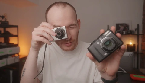 Photographer holding a vintage film camera in one hand and a digital camera in the other.