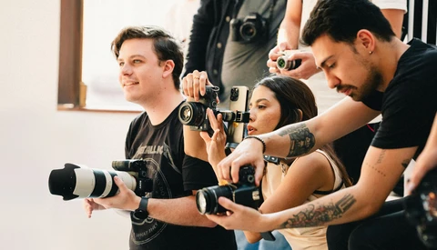 Photography workshop participants holding professional cameras and lenses during a hands-on training session.
