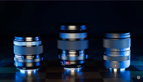 Three vintage camera lenses with blue and silver finishes arranged against a dark background.