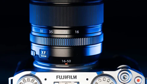 Fujifilm camera body with blue zoom lens showing focal length markings 16-50mm.