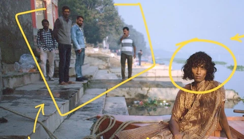 Woman in gold garment in foreground with yellow annotation lines connecting to group of men standing on street in background.