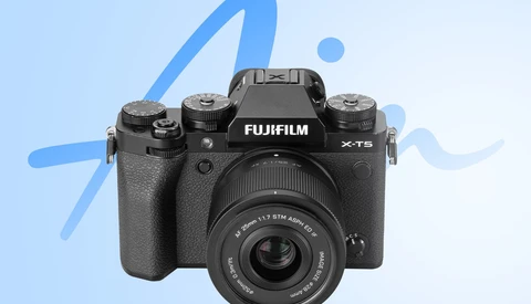 Fujifilm X-T5 mirrorless camera with attached lens against blue abstract background.