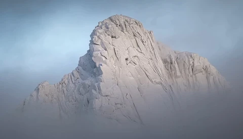 Snow-covered rocky peak emerging from thick fog and mist under overcast sky.