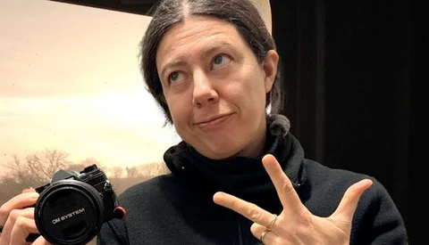 Photographer holding a compact camera while gesturing during discussion or demonstration.