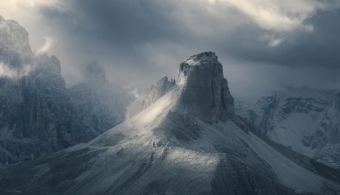 Snow-covered mountain peak rising through clouds in dramatic alpine landscape.