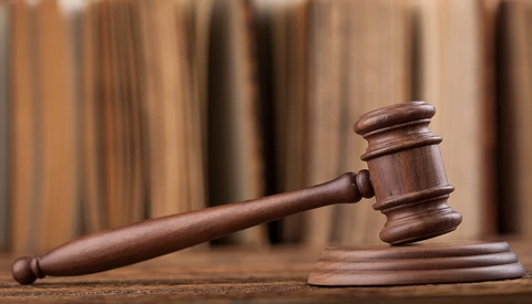 Wooden gavel and sound block on a textured surface with blurred curtains in the background.