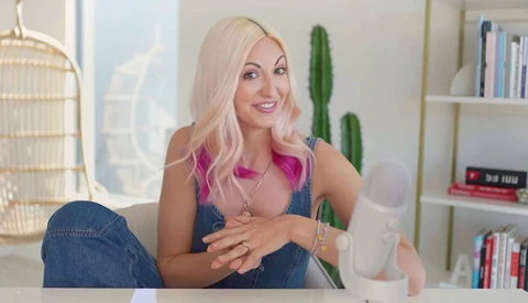 Woman with platinum blonde and pink hair sitting at desk in bright, minimalist home office.