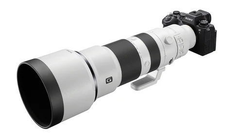 Sony mirrorless camera with white and black telephoto zoom lens mounted on top.