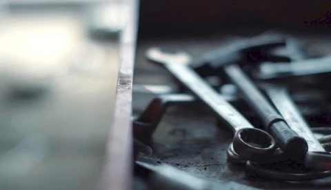 Close-up of wrenches and tools arranged on a dark surface with selective focus.