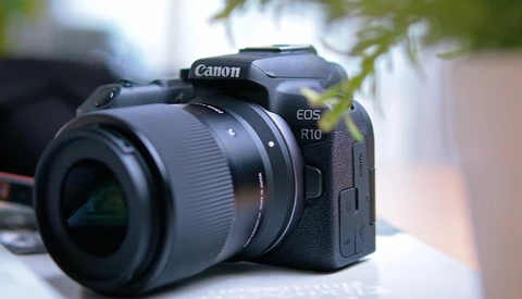 Canon EOS R10 mirrorless camera with attached RF-mount lens on outdoor surface.