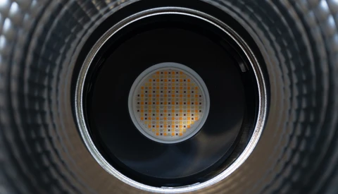 Looking directly into a cylindrical metal duct with concentric ridged walls and a perforated metal grate at the center.