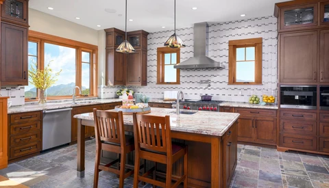 Bright kitchen interior with wood cabinetry, marble island, and geometric tile backsplash.