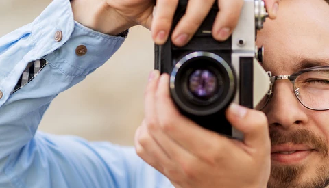 Photographer holding a rangefinder film camera up to his eye to compose a shot.
