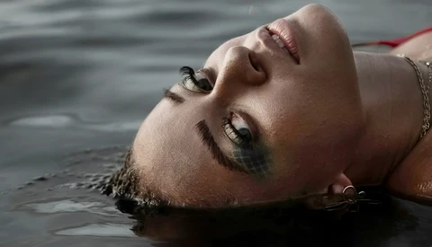 Person floating on their back in water with eyes closed and serene expression.