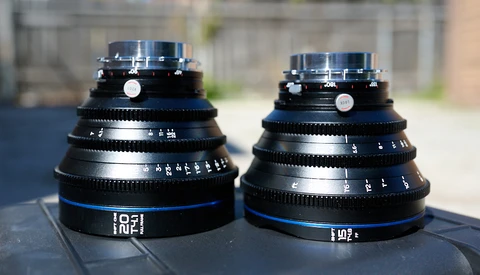 Two vintage cinema lenses with blue accents displayed side by side outdoors.