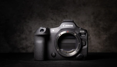 Canon EOS R5 Mark II mirrorless camera body without lens, shown front-facing against dark textured background.