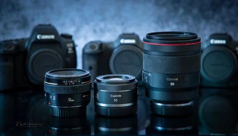 Canon EF 50mm prime lenses arranged in front of Canon DSLR camera bodies against a textured blue background.