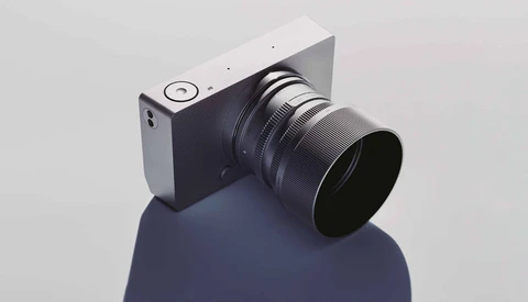 Mirrorless camera with interchangeable lens mounted on a reflective blue-gray sphere.