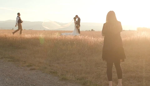 Four people standing in a dry, golden field at golden hour with backlighting creating silhouettes.