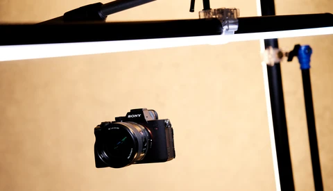 Sony mirrorless camera positioned on a cream-colored photography backdrop with studio lighting setup visible above.