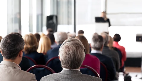 Rear view of audience members seated in rows during an indoor presentation or conference event.
