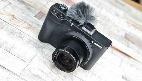 Canon EOS M6 Mark II compact camera with attached microphone on whitewashed wooden surface.