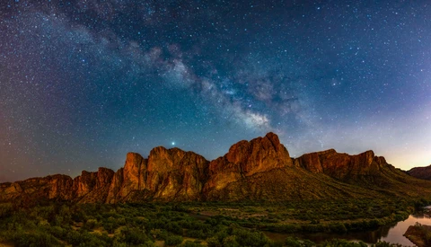 Desert rock formations silhouetted against a starry night sky with the Milky Way visible overhead.