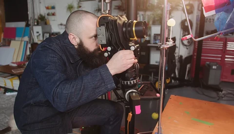 Photographer using a large format camera on a tripod in a workshop studio.