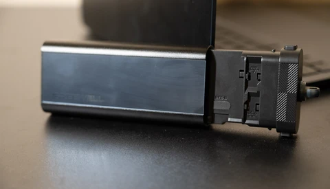 External hard drive with blue metallic casing and black connector module on desk surface.