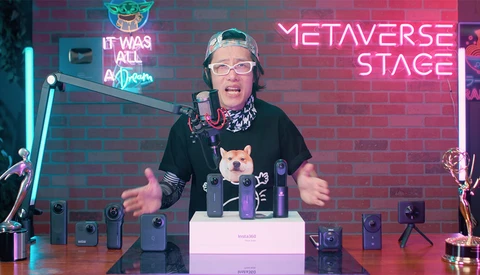 Streamer at desk with microphone, headphones, and ring light setup against neon brick wall backdrop.