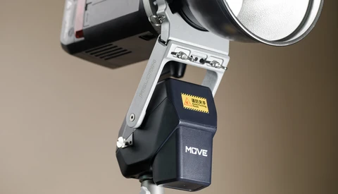 Flash unit with white bracket mounted on light stand against neutral background.