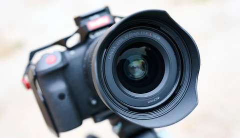 Close-up of a mirrorless camera with wide-angle lens mounted on a tripod, shot from the front.